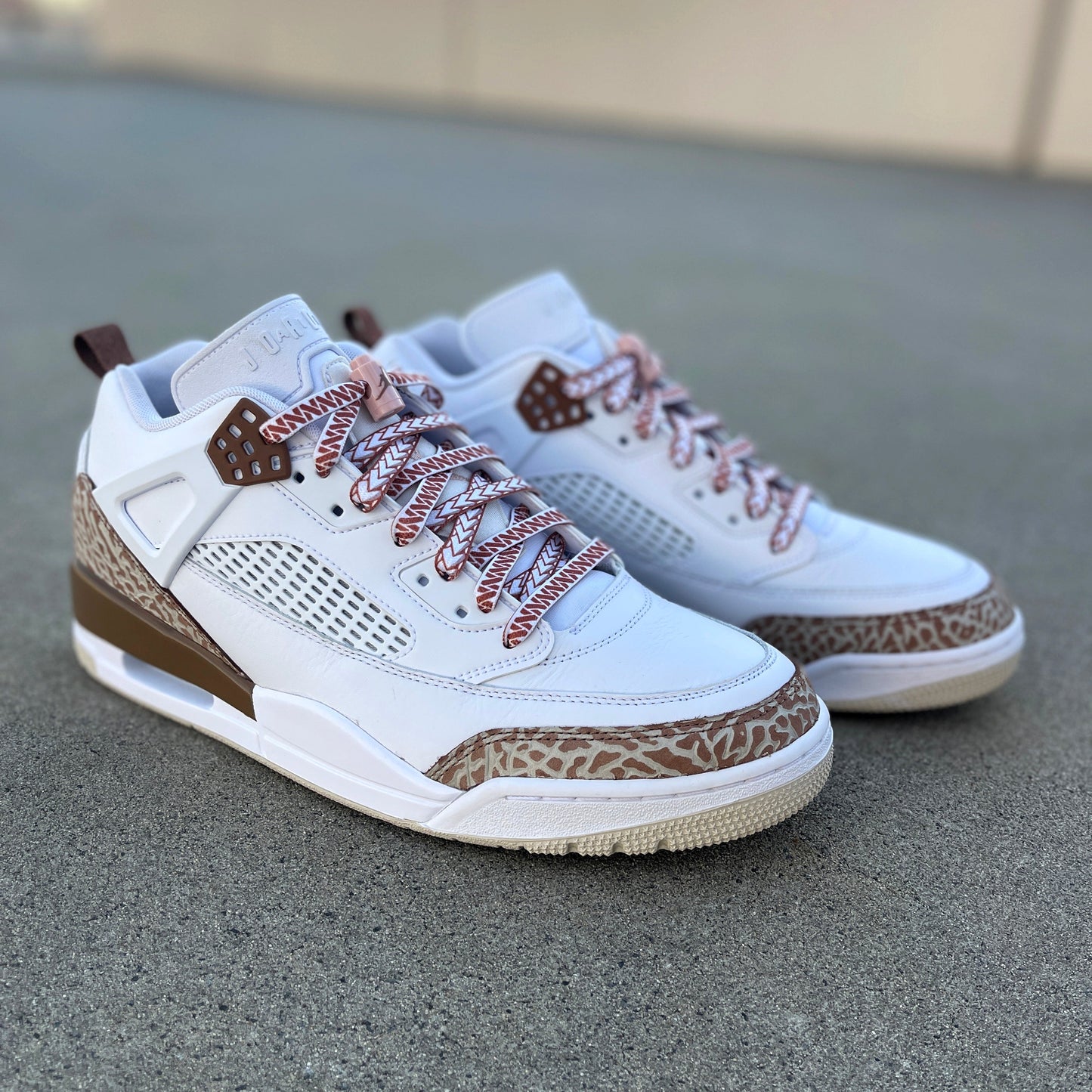 jordan spizikes with white nesia shoelaces with brown spear pattern on cement carpark background