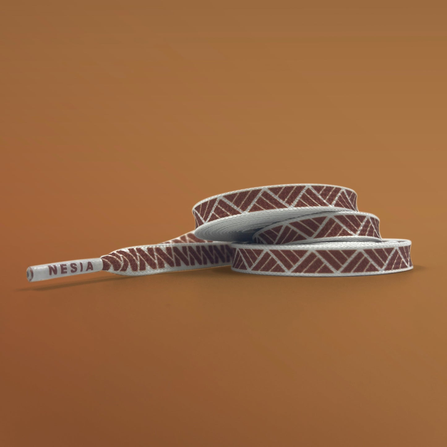Nesia shoeslaces brown tapa pattern on white laces on a brown studio background