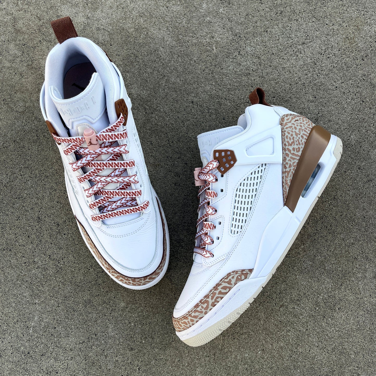 jordan spizikes with white nesia shoelaces with brown spear pattern on cement background