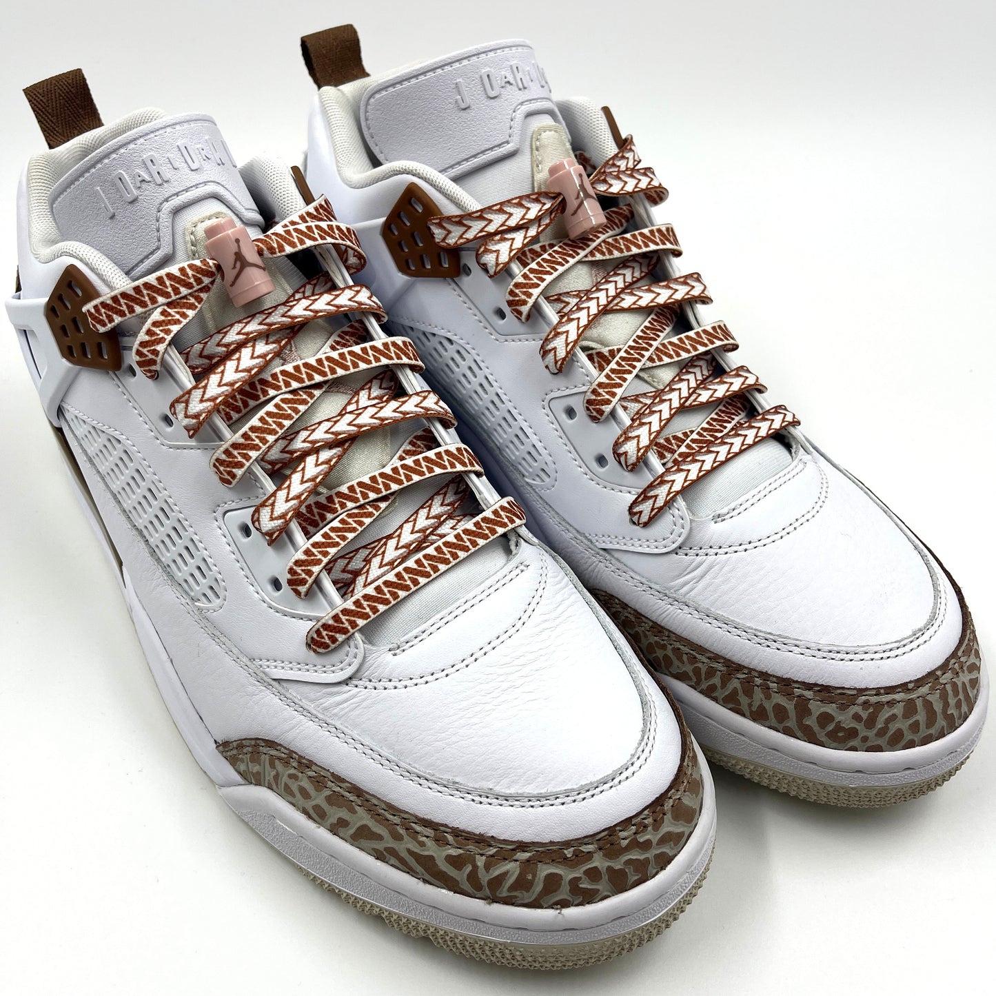 Jordan spizikes with white nesia shoelaces with brown spear patterns on white studio background